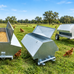 Chicken-feeders-and-drinkers-for-poultry-in-a-grassy-farm-field-with-chickens-nearby.png